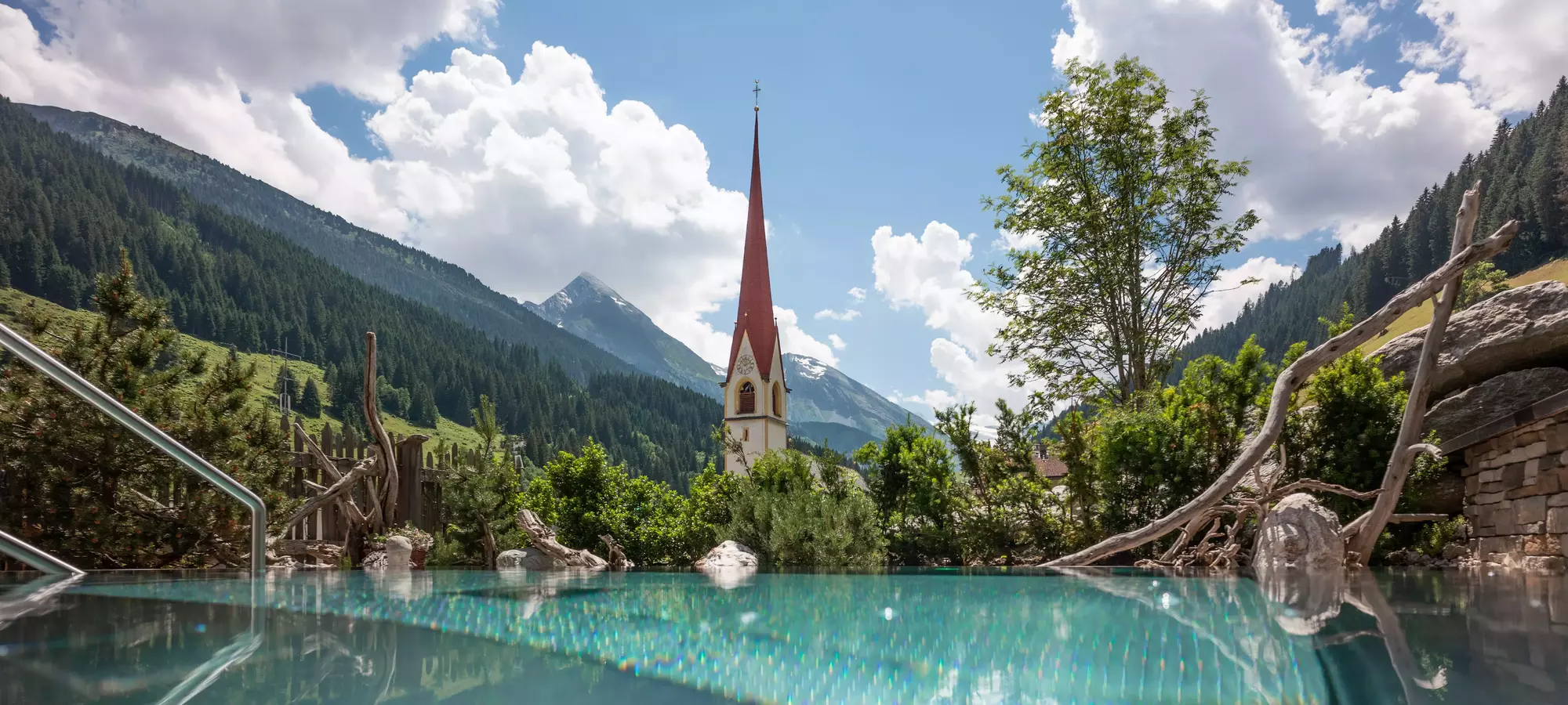 Blick über den Pool des Berghüttendorfs Anno Dazumal auf den Kirchturm